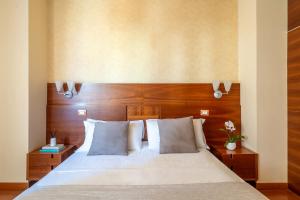 a bedroom with a white bed with a wooden headboard at Hotel Gala in Pesaro