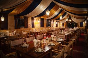 a dining room with tables and chairs and curtains at Erg Chigaga Luxury Camp in El Gouera