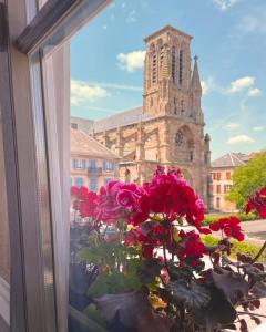 a window with flowers in front of a church at Hôtel Restaurant Chez Henriette in Phalsbourg