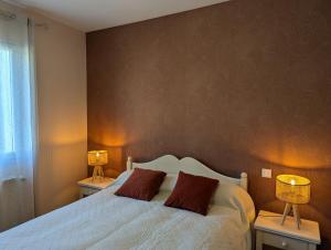 a bedroom with a bed with two lamps on two tables at Bellevue in Châteaubernard
