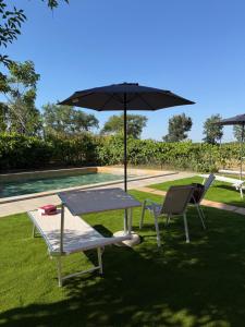 a table and two chairs and an umbrella next to a pool at Podere Tre Berte - The Sleeping Beauty in Acquaviva