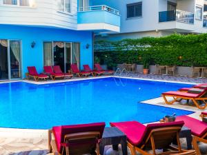 a swimming pool with red chairs and a hotel at Hawaii Suite Beach Hotel in Alanya