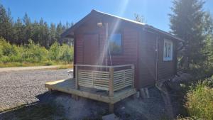 a small red cabin with a porch and a door at Paradise cottage w sea view in Brännöviken 5, Lögdeå in Lögdeå