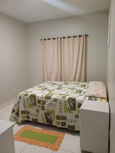 a bedroom with a bed with a blanket on it at Casa com varanda, garagem e cozinha completa in Formosa