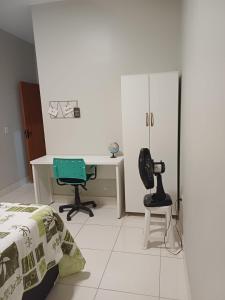 a bedroom with a bed and a desk and a chair at Casa com varanda, garagem e cozinha completa in Formosa