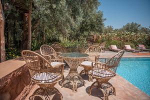 a group of chairs and a table next to a pool at Ecolodge Dar bouhouta in Tahannout