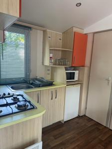 a kitchen with wooden cabinets and a stove top oven at Camping Le Capdeville in Carcans