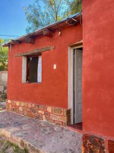a red building with a door and a window at Cabañas tilcara sarahuayco in Tilcara
