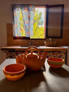 a teapot and bowls on a table in a kitchen at Cabañas tilcara sarahuayco in Tilcara