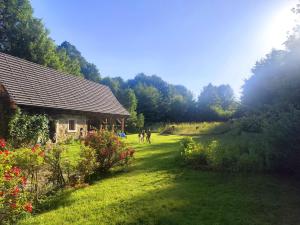 a group of people walking in a yard next to a house at Chatka zimorodka 1790 z sauną in Pielgrzymka