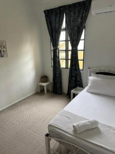 a bedroom with a white bed and a window at Casa Sara in Nilai