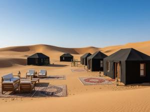 a group of black tents in the desert at Erg Chigaga Luxury Camp in El Gouera