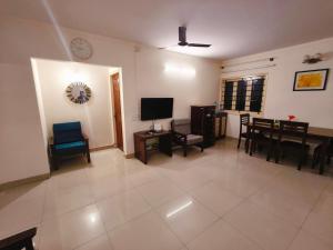 a living room with a television and a table and chairs at 2bhk furnished Richmond town in Bangalore
