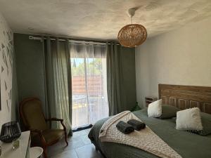 a bedroom with a bed with a chair and a window at Les Gîtes W''elles''come in Cotignac