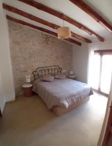 a bedroom with a bed and a brick wall at casa LHort in Benisili