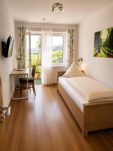 a bedroom with a bed and a desk and a window at Bed and Breakfast - Rheingauer Hof in Oestrich-Winkel
