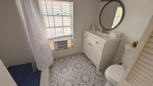 a bathroom with a toilet and a sink and a mirror at The Independent Inn in Key West +14 photos