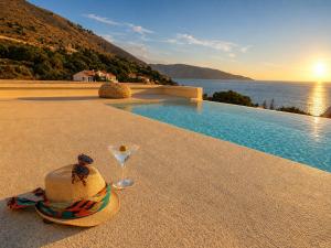 a hat and a wine glass sitting next to a swimming pool at Cabana Retreat in Agia Effimia