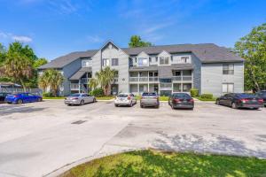a large apartment building with cars parked in a parking lot at Tranquil Condo with Pond View in Charleston