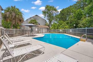 a swimming pool with lounge chairs and an umbrella at Tranquil Condo with Pond View in Charleston