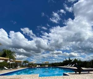 a blue swimming pool with a cloudy sky at cabañas aleli in Embalse