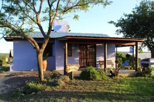 a blue house with a tree in front of it at cabañas aleli in Embalse