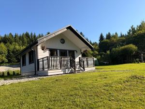 a small house with a porch on a grass field at Las Się Żyje in Lutowiska