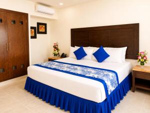 a bedroom with a large bed with blue and white pillows at Hotel Catedral Valladolid Yucatan in Valladolid