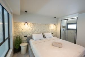 a bedroom with a large white bed and a shower at NOMA Suites in Kalamata