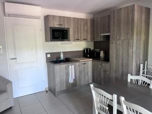 a kitchen with wooden cabinets and a table with chairs at Agapanthe in Remoulins