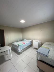 a room with two beds and a table in it at Pousada do Gil in Iguatu