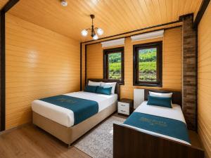 two beds in a room with two windows at Şimo Suite Otel in Uzungöl
