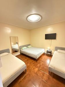 a room with two beds and a mirror and a tv at Lisboa Parque Guest House in Lisbon