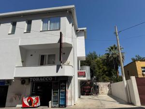 a white building with a store in front of it at Hotel Djakbe in Tirana