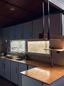 a kitchen with white cabinets and a sink and a window at The Margallia in Islamabad