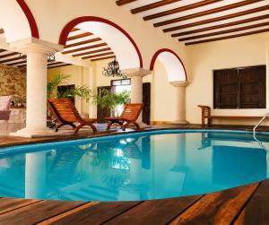 a pool in a house with two chairs and a swimming pool at Hotel Catedral Valladolid Yucatan in Valladolid