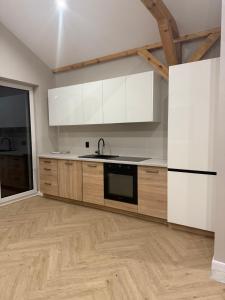 una cucina con mobili bianchi e pavimento in legno di Chill and Grill - Modlin Airport Apartamenty na wynajem a Wola Smolana