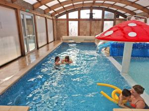 a group of people in a pool with a red umbrella at Zefir SPA in Polańczyk +69 photos