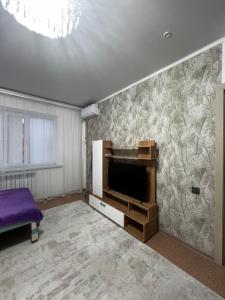 a living room with a tv and a purple couch at Квартира in Balqash