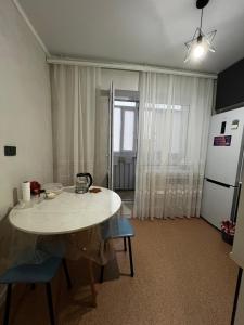 a kitchen with a white table and a refrigerator at Квартира in Balqash