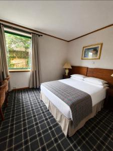 a hotel room with a large bed and a window at Loch Ness Lodge Hotel in Drumnadrochit