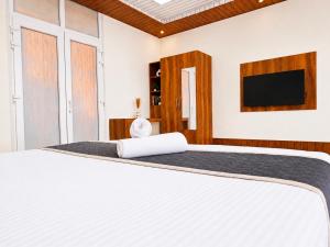 a bedroom with a white bed and a flat screen tv at SS Luxury Comforts - Twin Sharing in Chikmagalūr