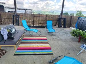 a patio with two blue chairs and a couch and a rug at Vila Seoska idila in Izvor