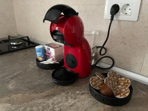 a red coffee maker sitting on a counter with cookies at Lena Apartment in Calafat