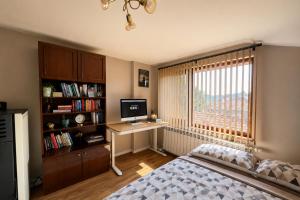 a bedroom with a bed and a desk and a window at Mountain View Apartment in Troyan