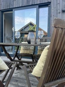a wooden table with two wine glasses on a porch at Brightside Suite in Kristiansand