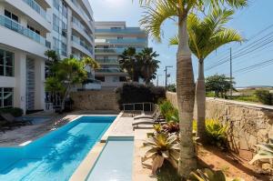 a swimming pool with palm trees next to a building at FLAT MANDAI PREMIUM - Cabo Frio in Cabo Frio
