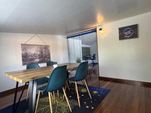 a dining room with a wooden table and blue chairs at La Maison Blanche, 2 bedrooms in Macouria