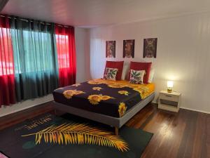 a bedroom with a bed with red curtains and a rug at La Maison Blanche, 2 bedrooms in Macouria