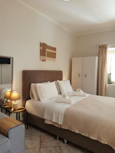 a bedroom with a large bed with white sheets and a chair at Feidiou 1, vol I in Egina